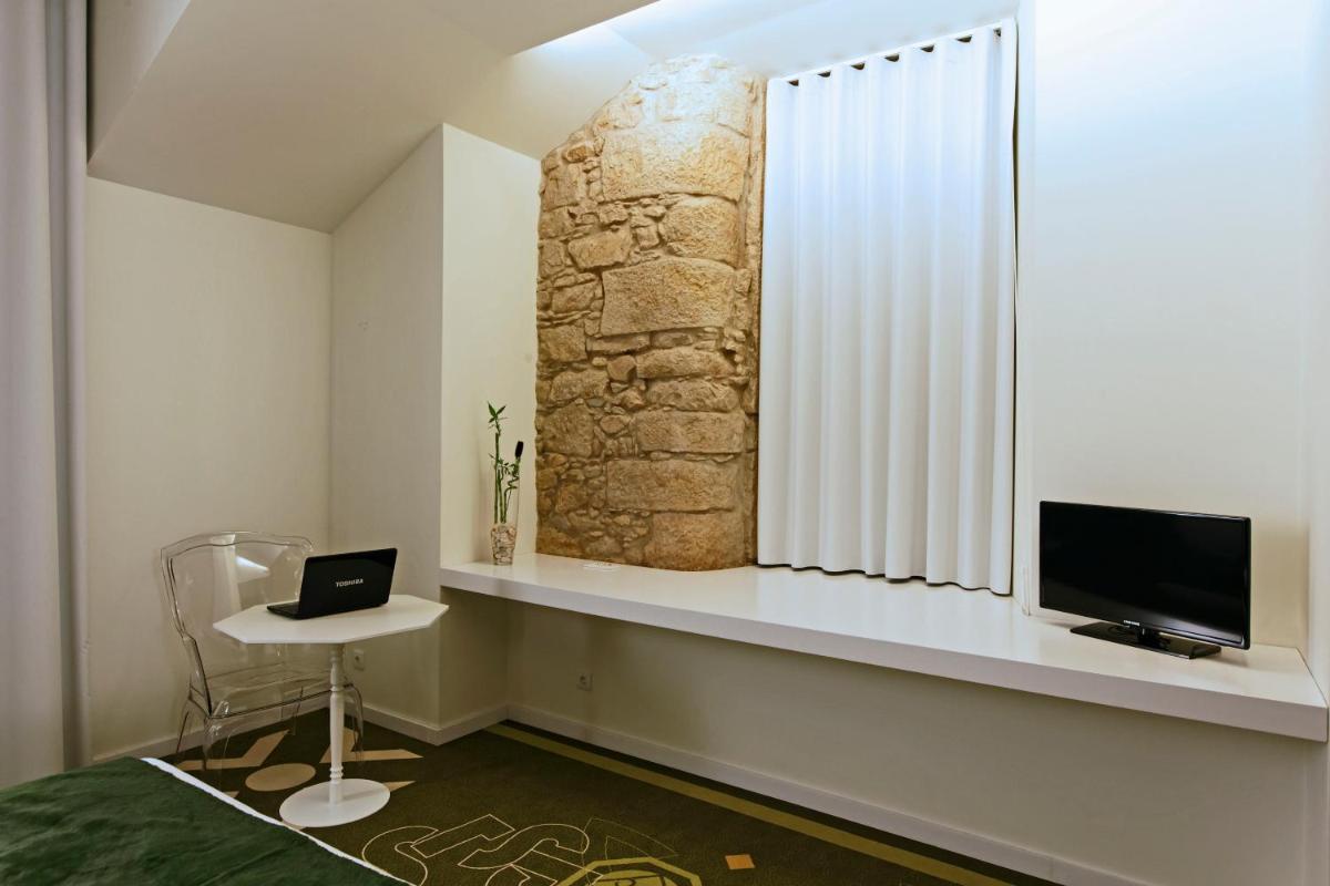 um quarto com uma secretária, uma televisão e uma janela em HD