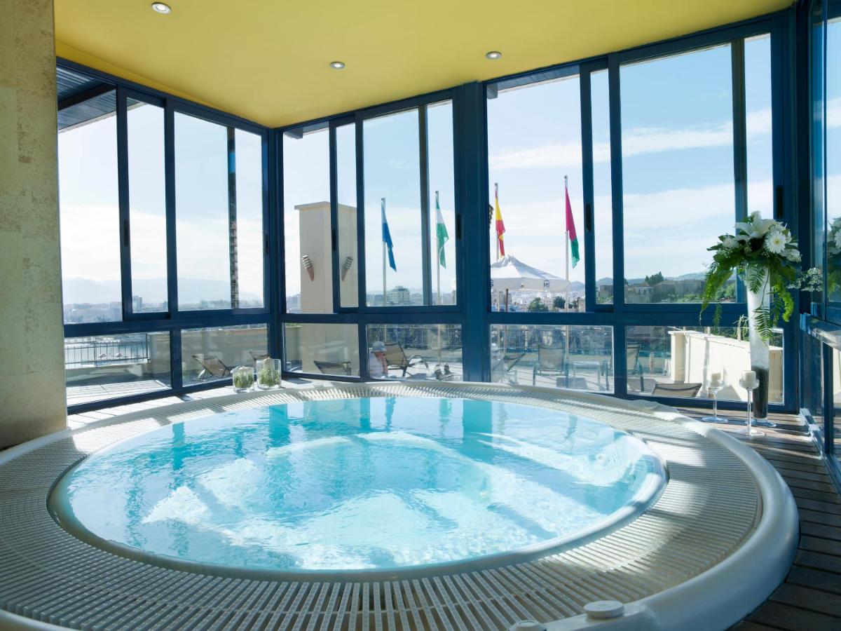 Una gran piscina en un edificio con ventanas. en Hotel MS Maestranza Málaga, en Málaga