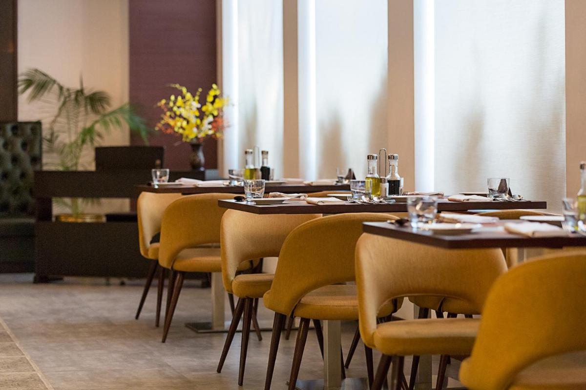 a dining room with tables and yellow chairs at The Accord Metropolitan in Chennai