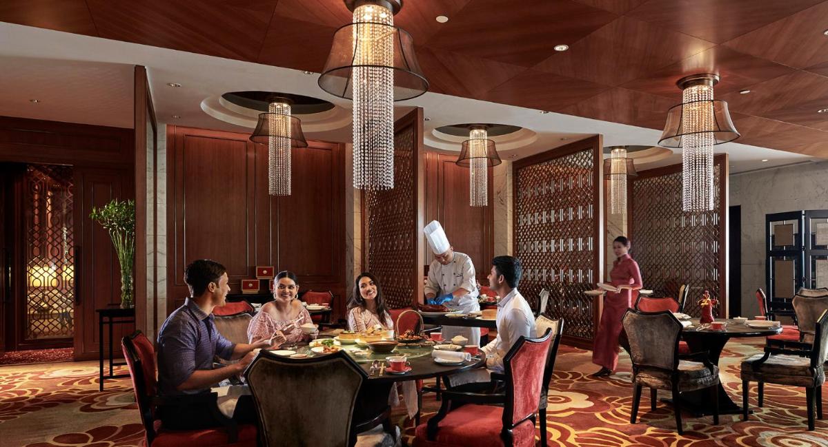 a group of people sitting at tables in a restaurant at Shangri-La Bengaluru in Bengaluru a group of people sitting at tables in a restaurant at Shangri-La Bengaluru in Bengaluru