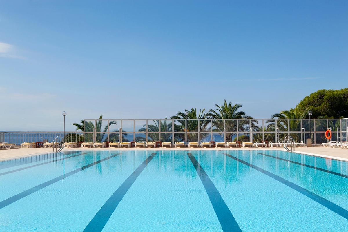 una gran piscina azul con sillas y el océano en Almadraba Park Hotel, en Roses 280 fotos más
