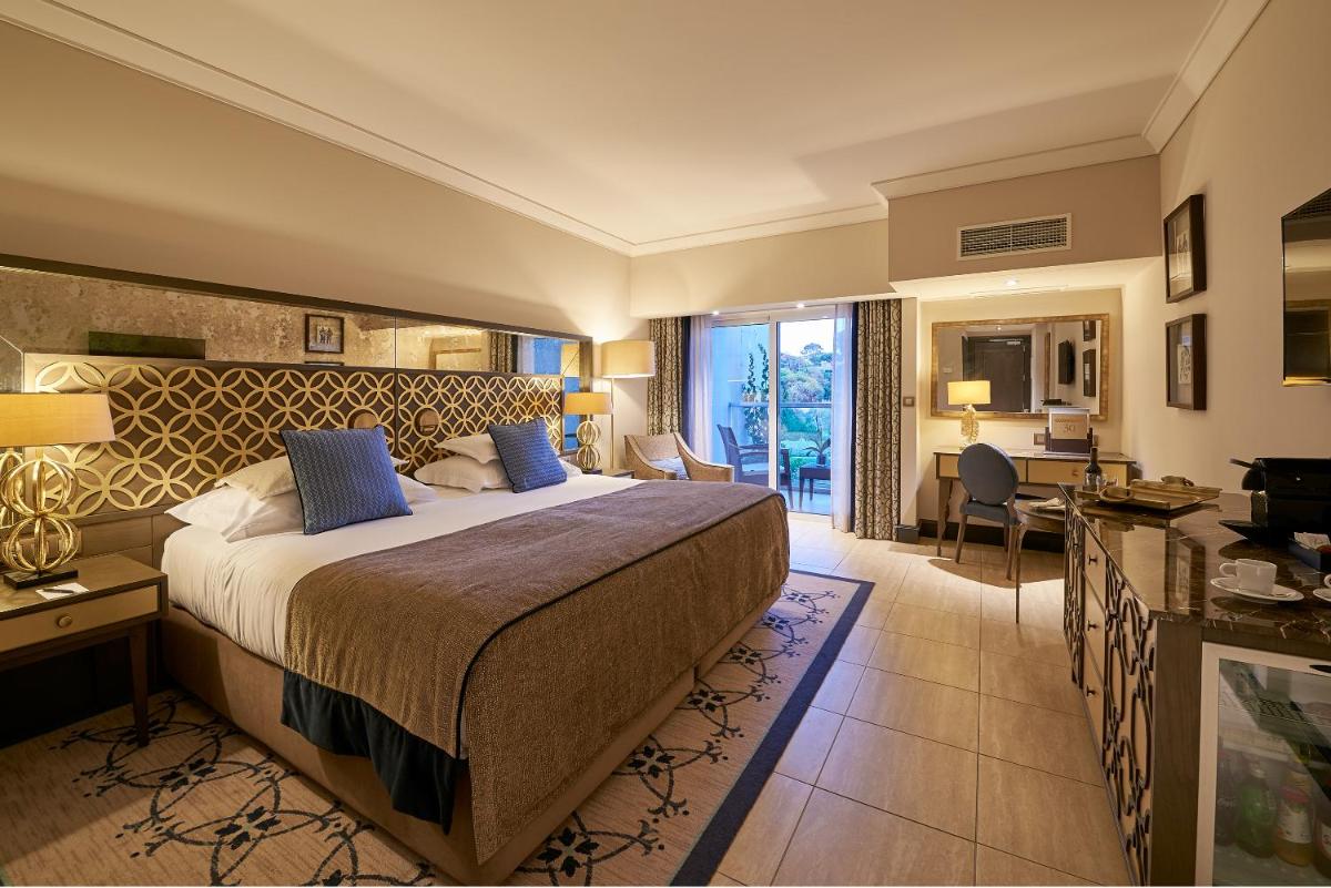 um quarto de hotel com uma cama grande e uma escrivaninha em Dona Filipa Hotel no Vale do Lobo