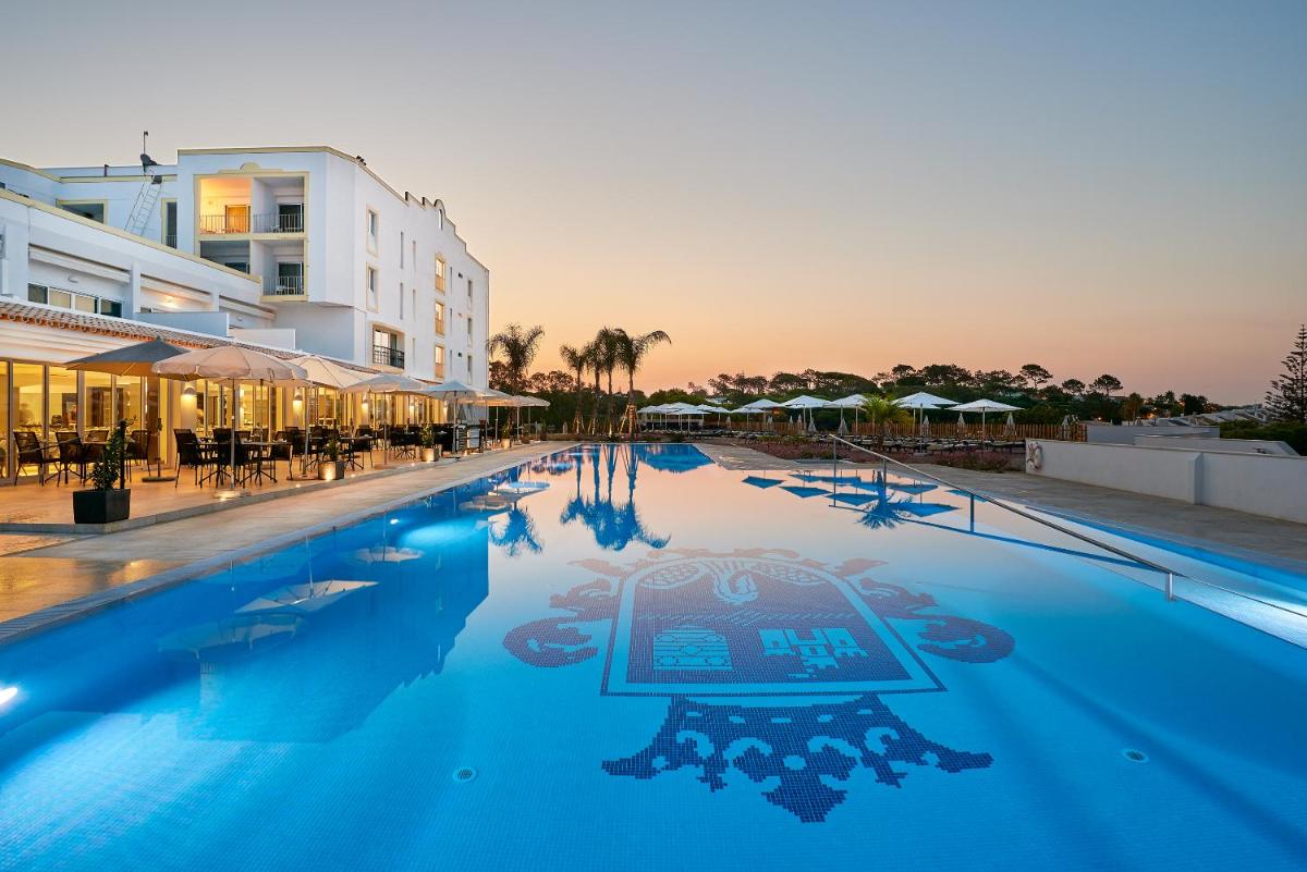 uma grande piscina com um hotel ao fundo em Dona Filipa Hotel no Vale do Lobo