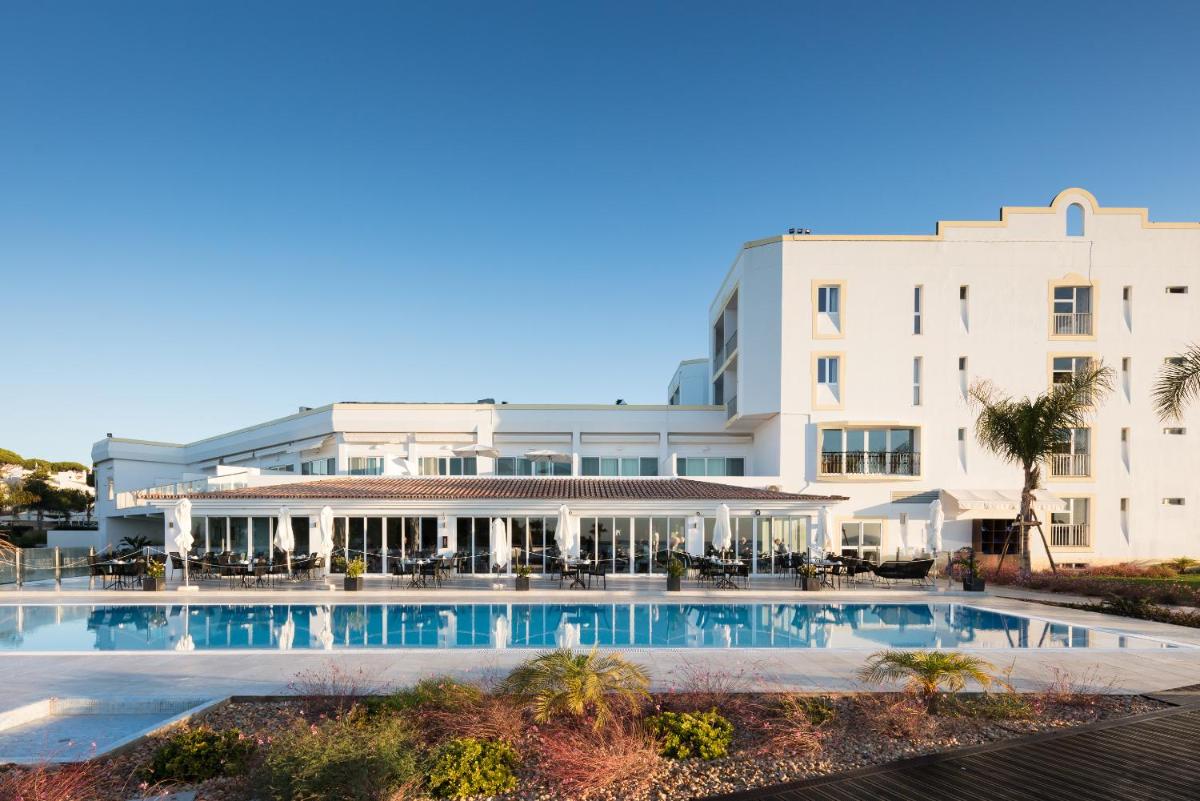 um hotel com piscina em frente a um prédio em Dona Filipa Hotel no Vale do Lobo