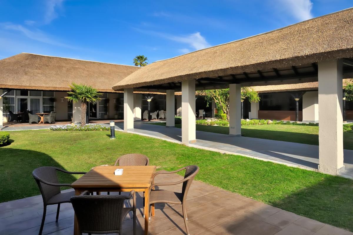 Un patio con mesa y sillas y un edificio. en Vincci Resort Costa Golf, en Chiclana de la Frontera