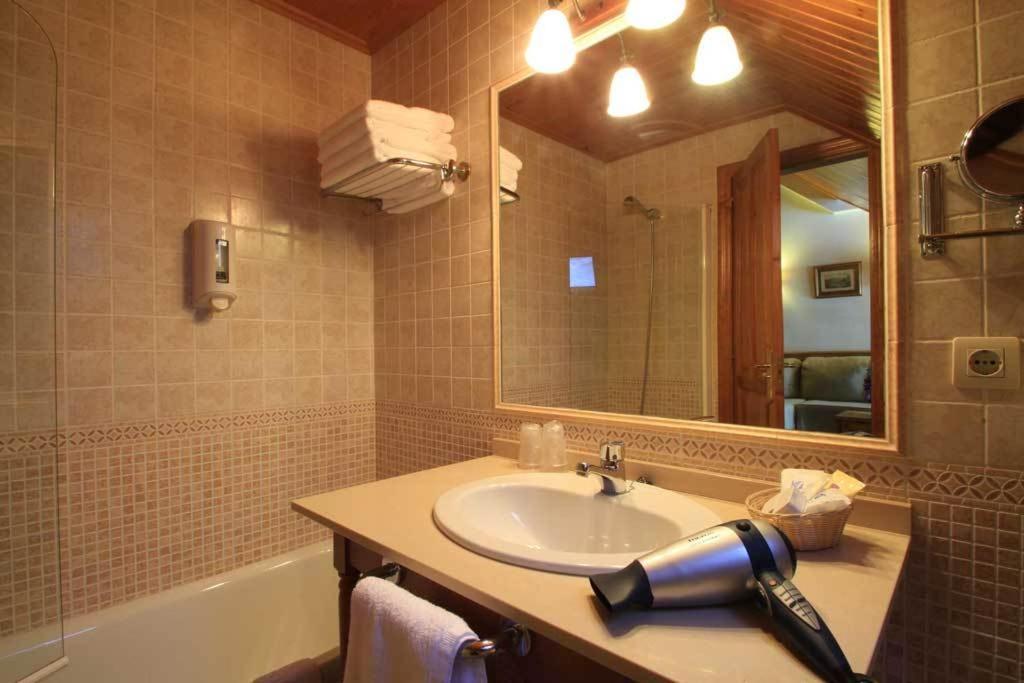 Un baño con lavabo, espejo y bañera. en Aparthotel Sarrato, en Sallent de Gállego