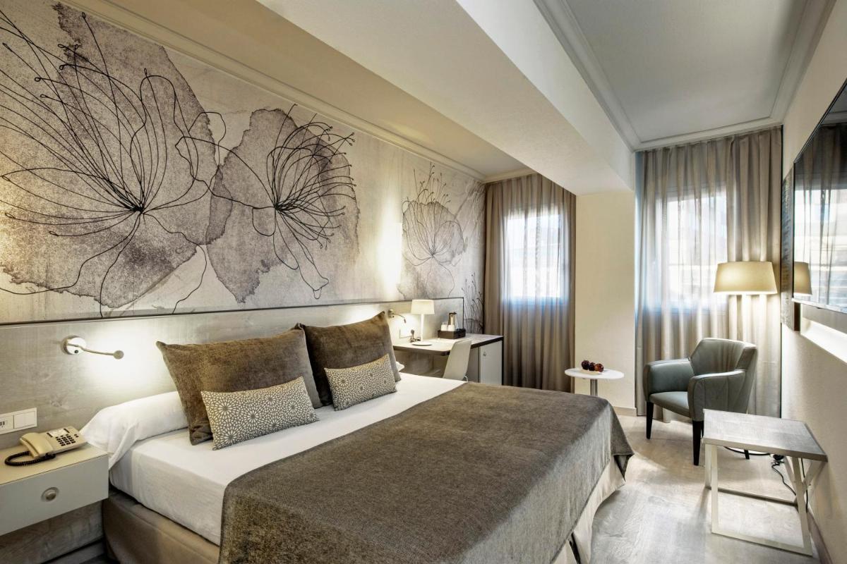 Una habitación de hotel con una cama grande y una silla. en Sallés Hotel Pere IV, en Barcelona