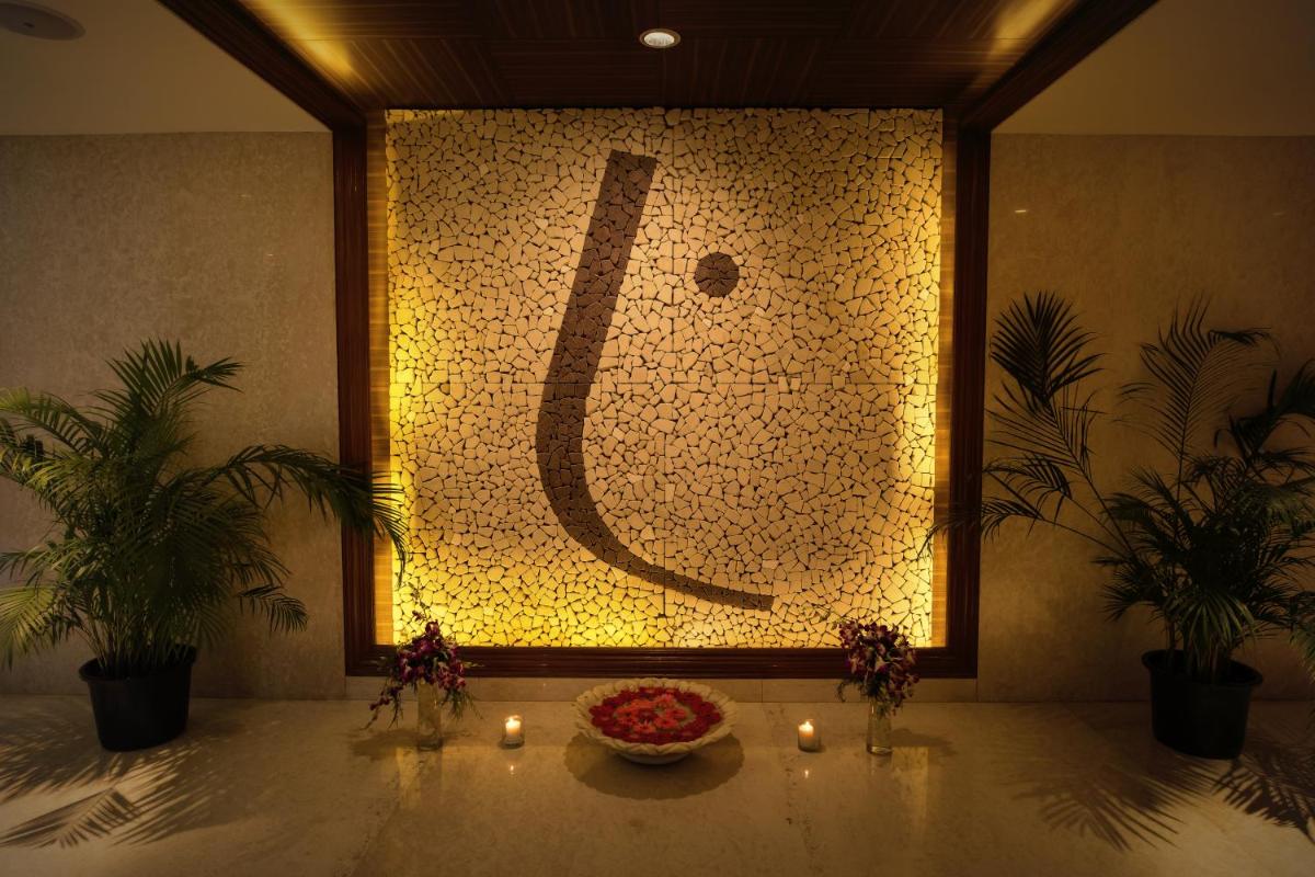 a wall with a letter j in a room with candles at The Lalit Chandigarh in Chandīgarh