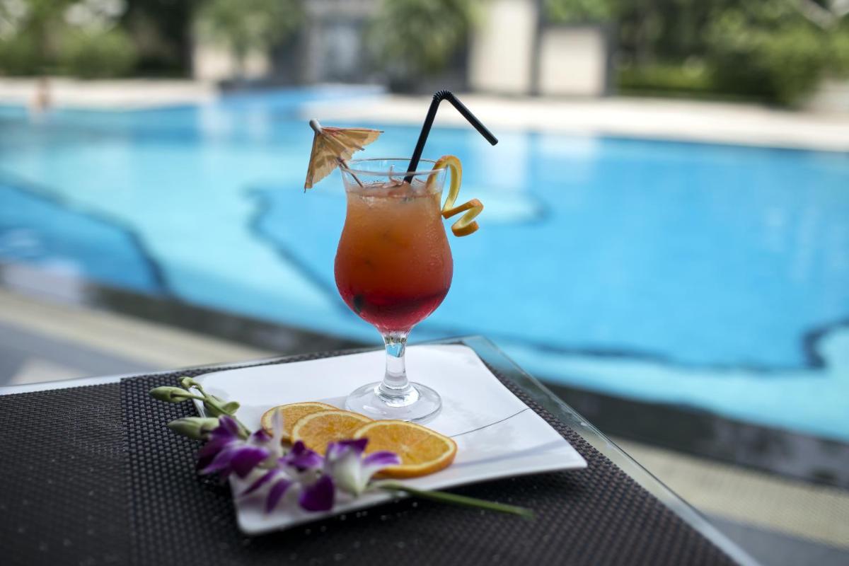 a drink sitting on a table next to a pool at The Lalit Chandigarh in Chandīgarh