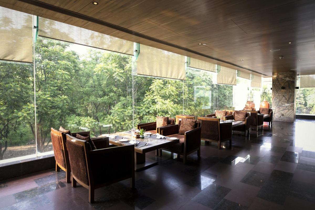 a restaurant with tables and chairs and large windows at The Lalit Chandigarh in Chandīgarh