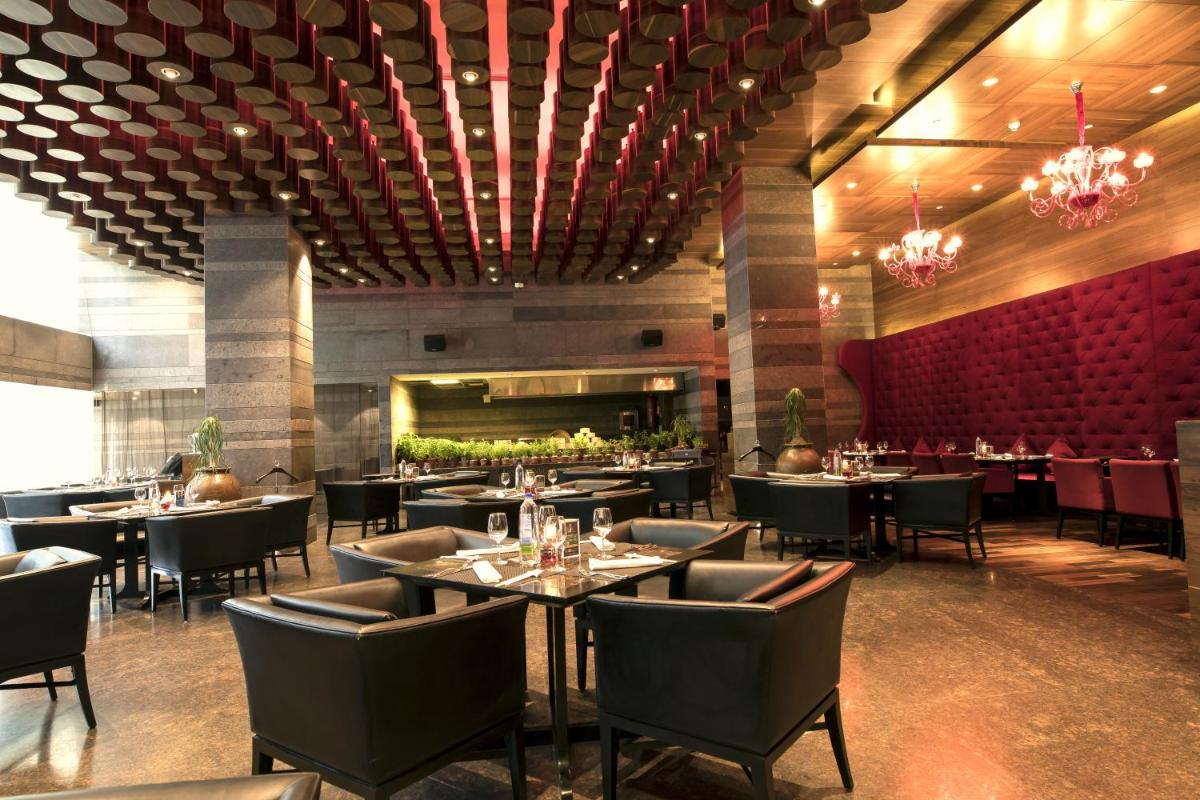 a restaurant with tables and chairs and a bar at The Lalit Chandigarh in Chandīgarh
