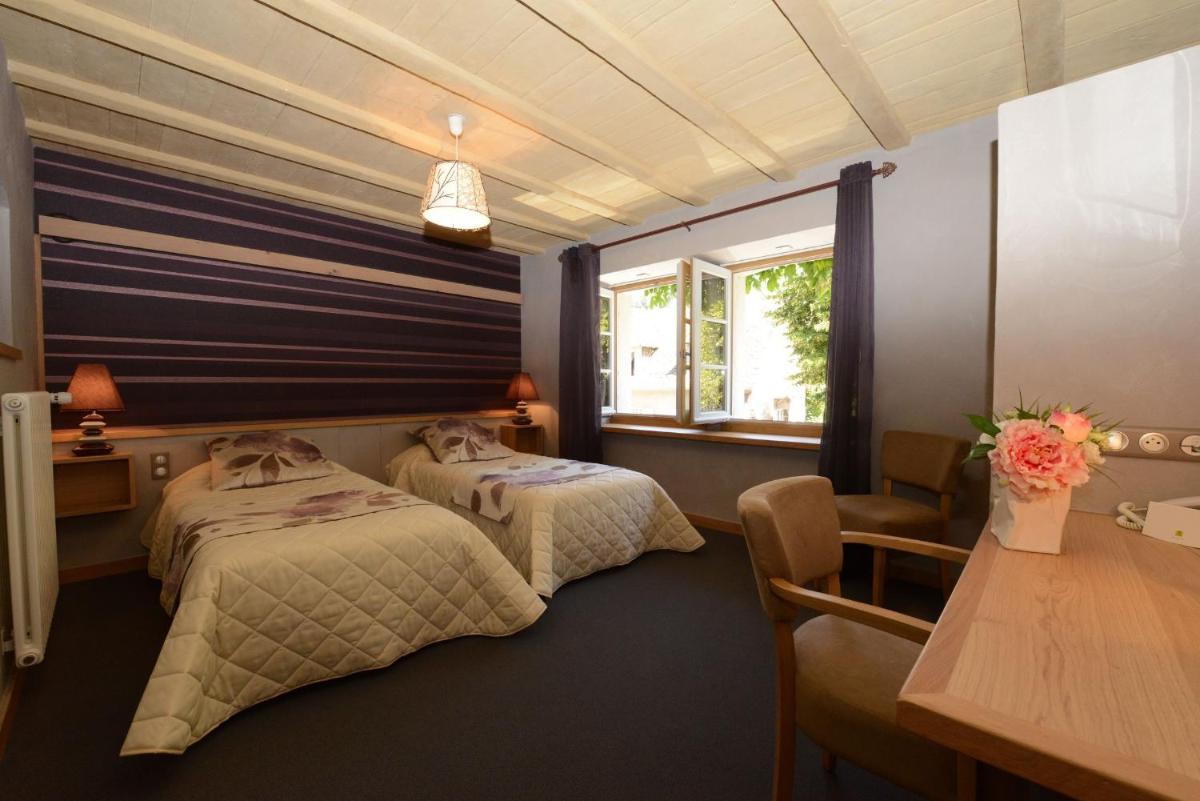 une chambre avec deux lits et un bureau et une fenêtre dans l'établissement Logis Hôtel Restaurant & Spa les Remparts, à Salers