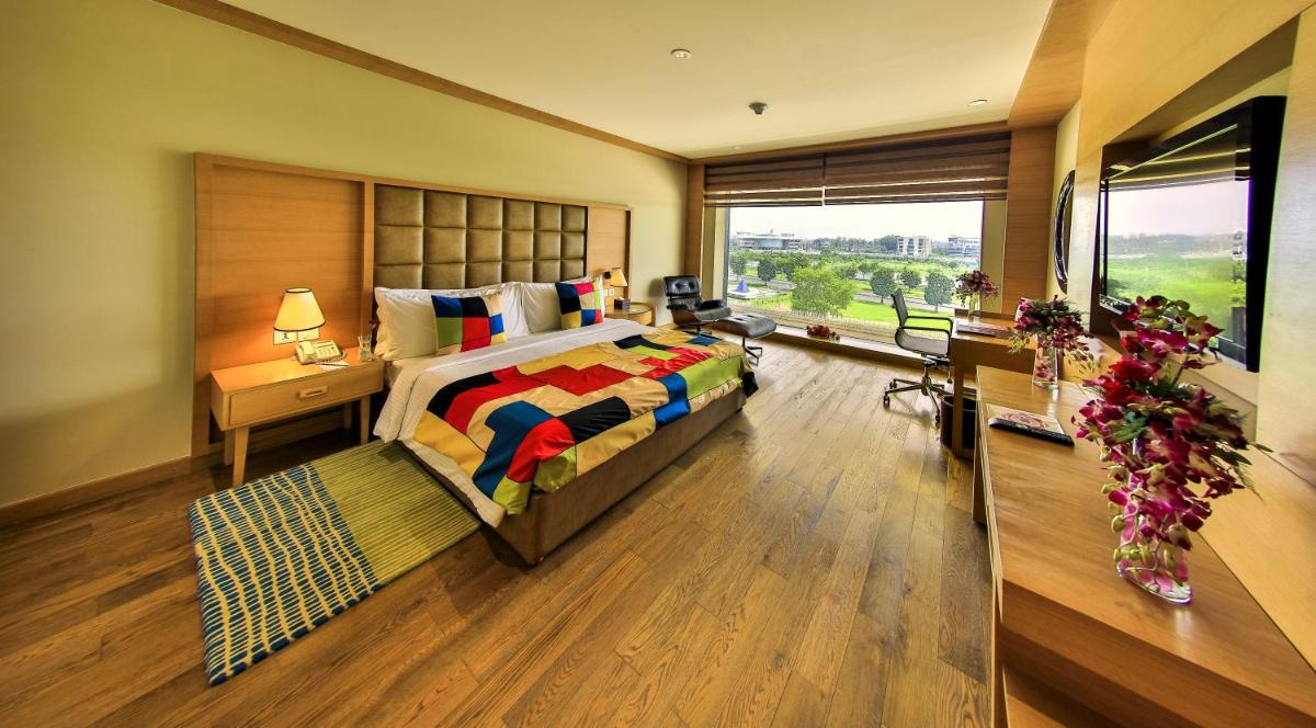 a bedroom with a large bed and a large window at The Lalit Chandigarh in Chandīgarh