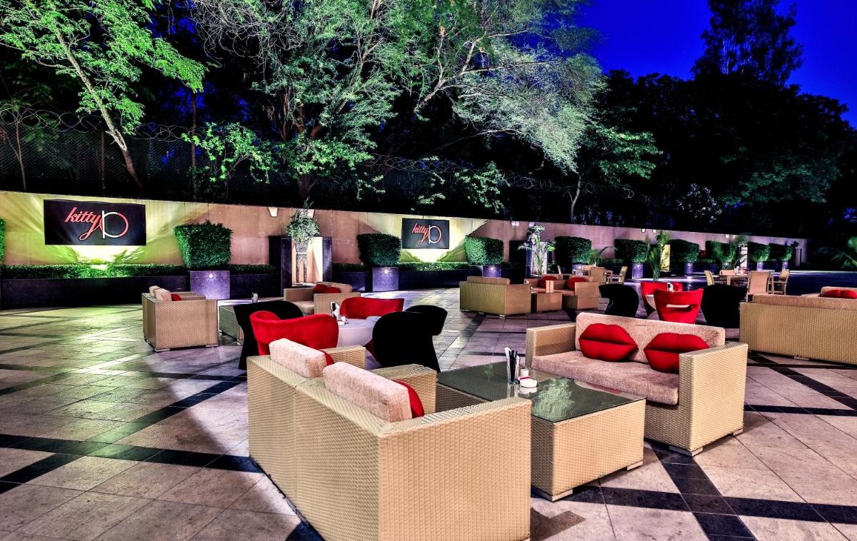 a patio with couches and tables with red pillows at The Lalit Chandigarh in Chandīgarh