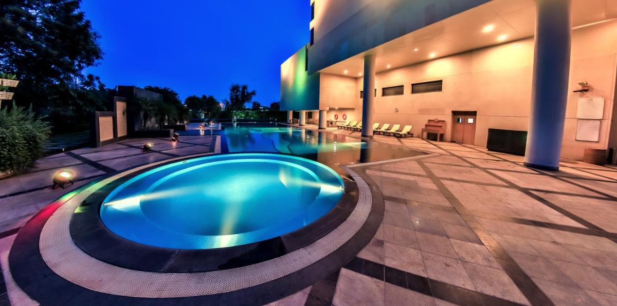 a swimming pool in front of a building at night at The Lalit Chandigarh in Chandīgarh