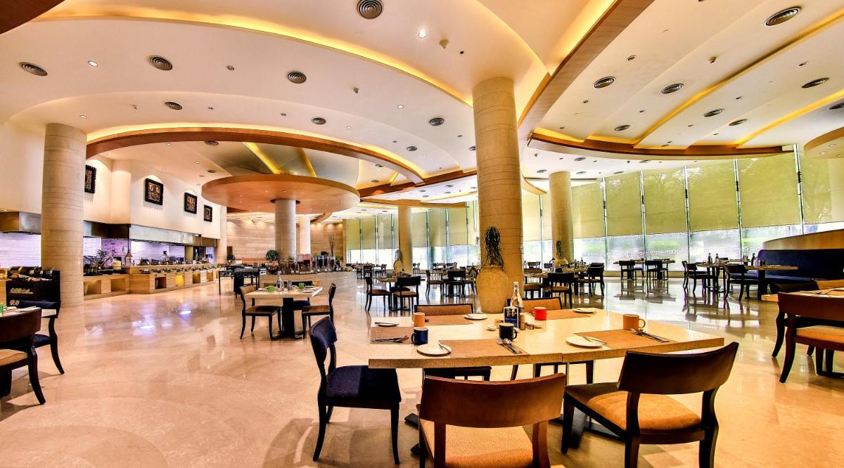 a restaurant with tables and chairs in a building at The Lalit Chandigarh in Chandīgarh
