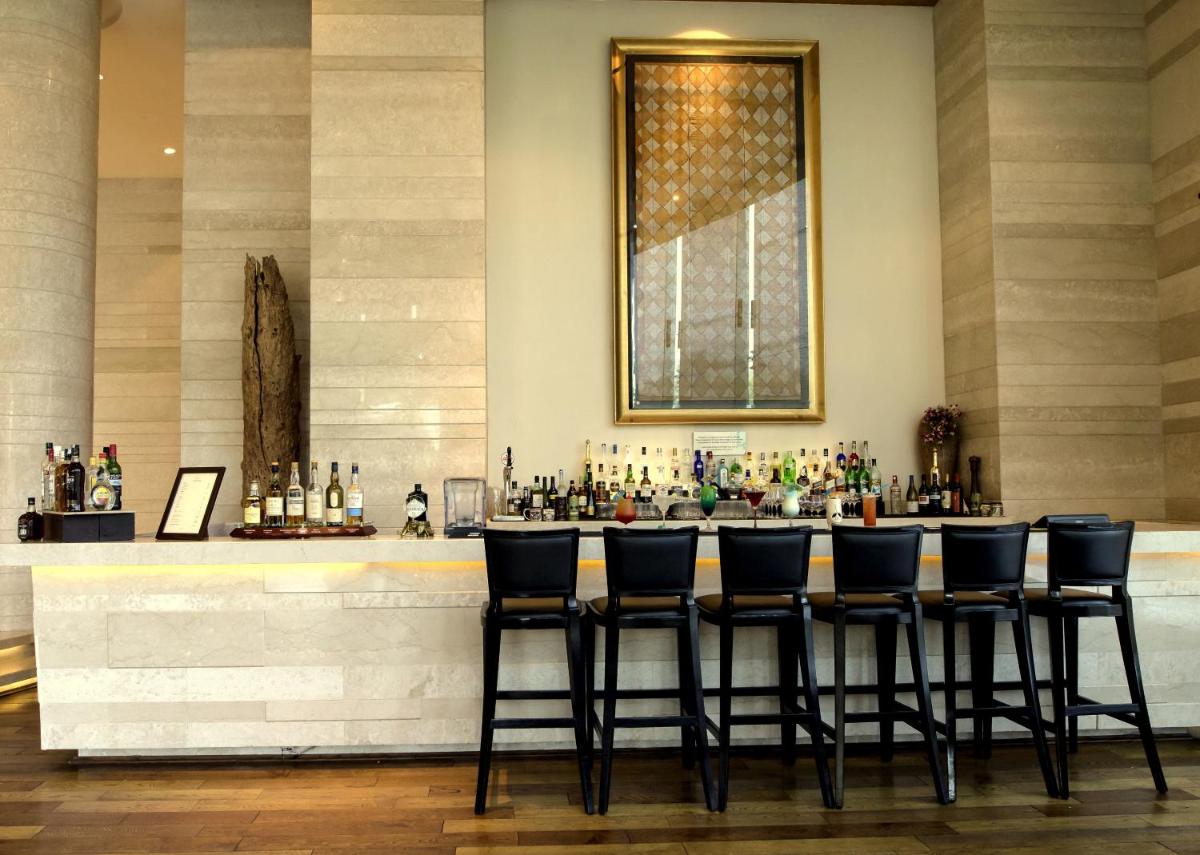 a bar with black stools in front of a counter at The Lalit Chandigarh in Chandīgarh