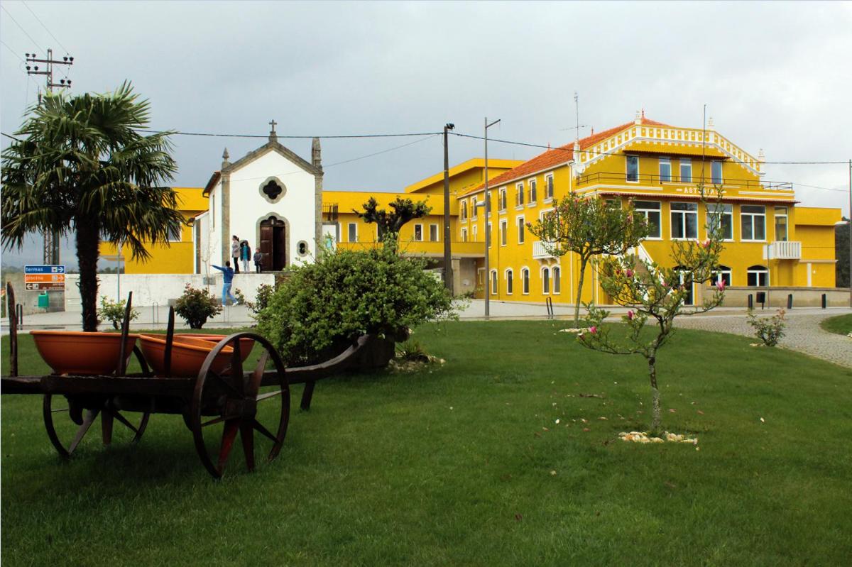 um parque com um banco na relva com edifícios em Palace Hotel Astúrias & Spa em Carvalhal