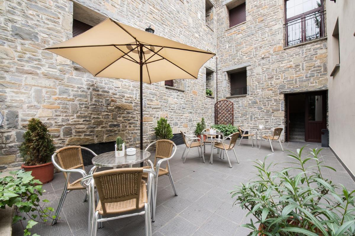 Un patio con una mesa y sillas y una sombrilla. en Hotel Villa Virginia, en Sabiñánigo
