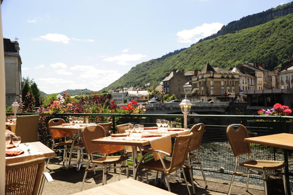 un restaurant avec des tables et des chaises sur un balcon dans l'établissement Logis Central Hôtel - Restaurant & Spa, à Bort-les-Orgues