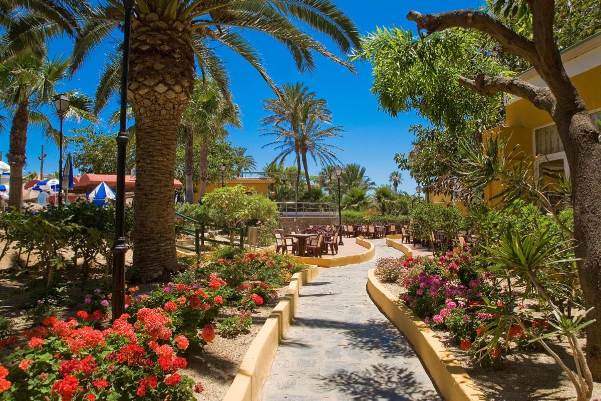 un jardín con flores y palmeras en el complejo en Playasol, en Roquetas de Mar