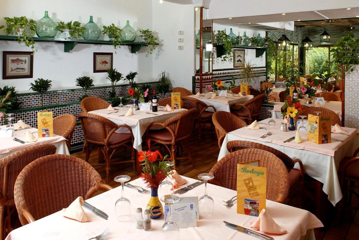 un restaurante con mesas blancas y sillas con flores. en Playasol, en Roquetas de Mar