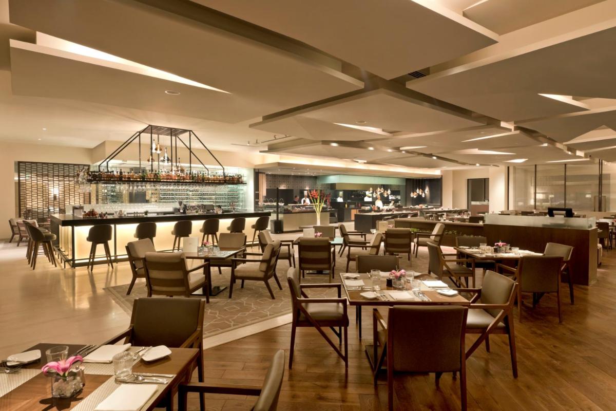a restaurant with tables and chairs and a bar at The Oberoi New Delhi in New Delhi a restaurant with tables and chairs and a bar at The Oberoi New Delhi in New Delhi