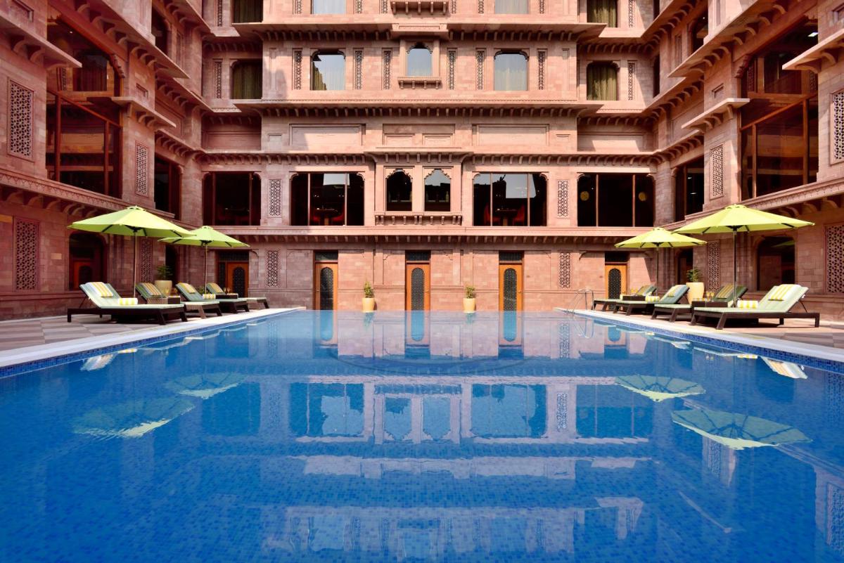 a swimming pool in a building with chairs and umbrellas at Radisson Jodhpur in Jodhpur