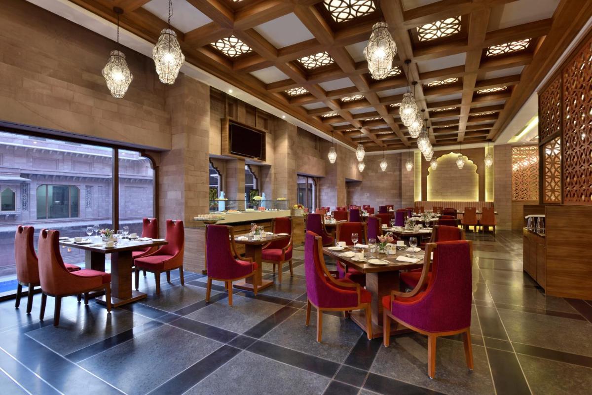 a dining room with tables and red chairs at Radisson Jodhpur in Jodhpur