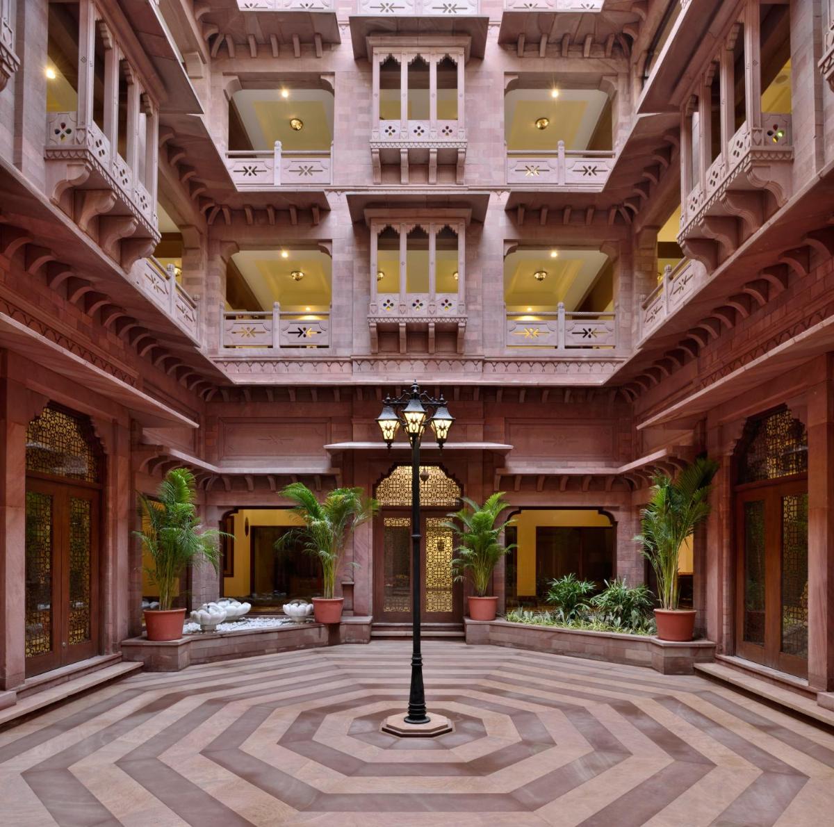 a large building with a courtyard with palm trees at Radisson Jodhpur in Jodhpur