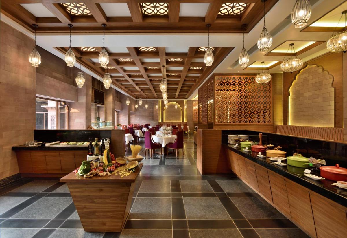 a large kitchen with tables and chairs in a restaurant at Radisson Jodhpur in Jodhpur