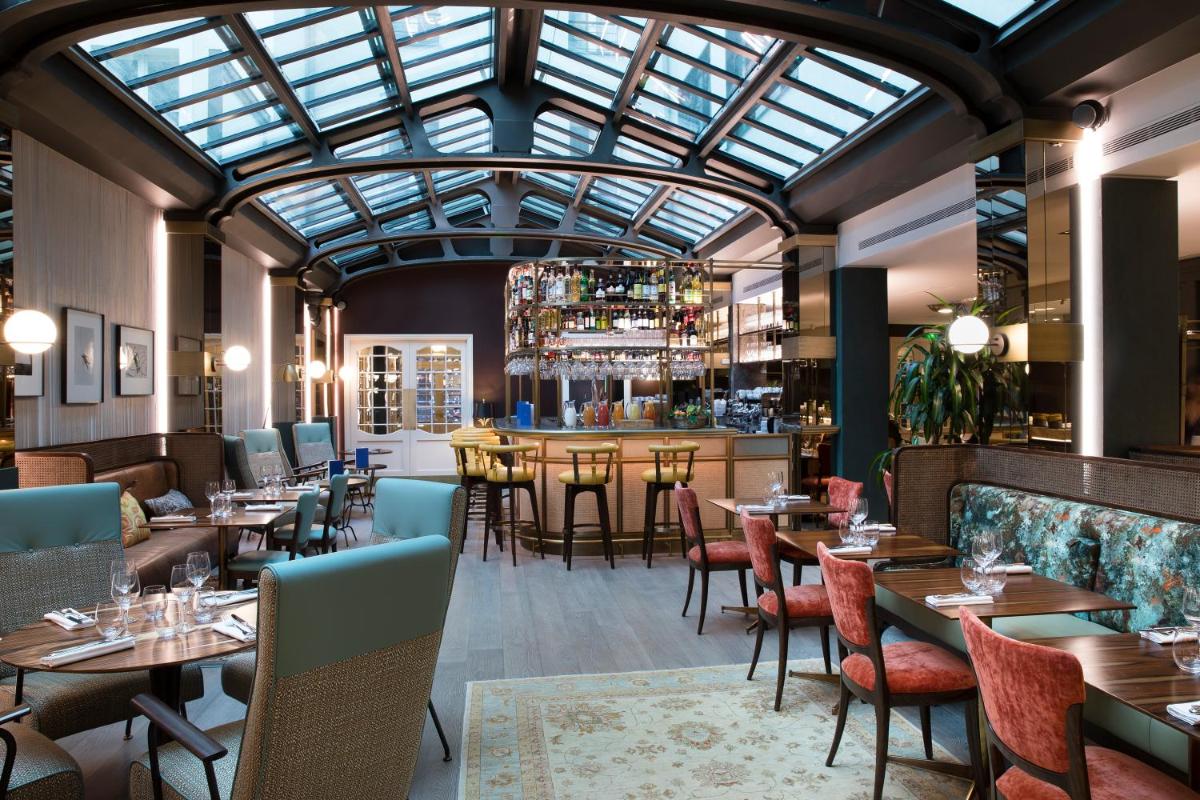 un restaurant avec des tables et des chaises et un plafond de verre dans l'établissement Maison Bréguet, à Paris