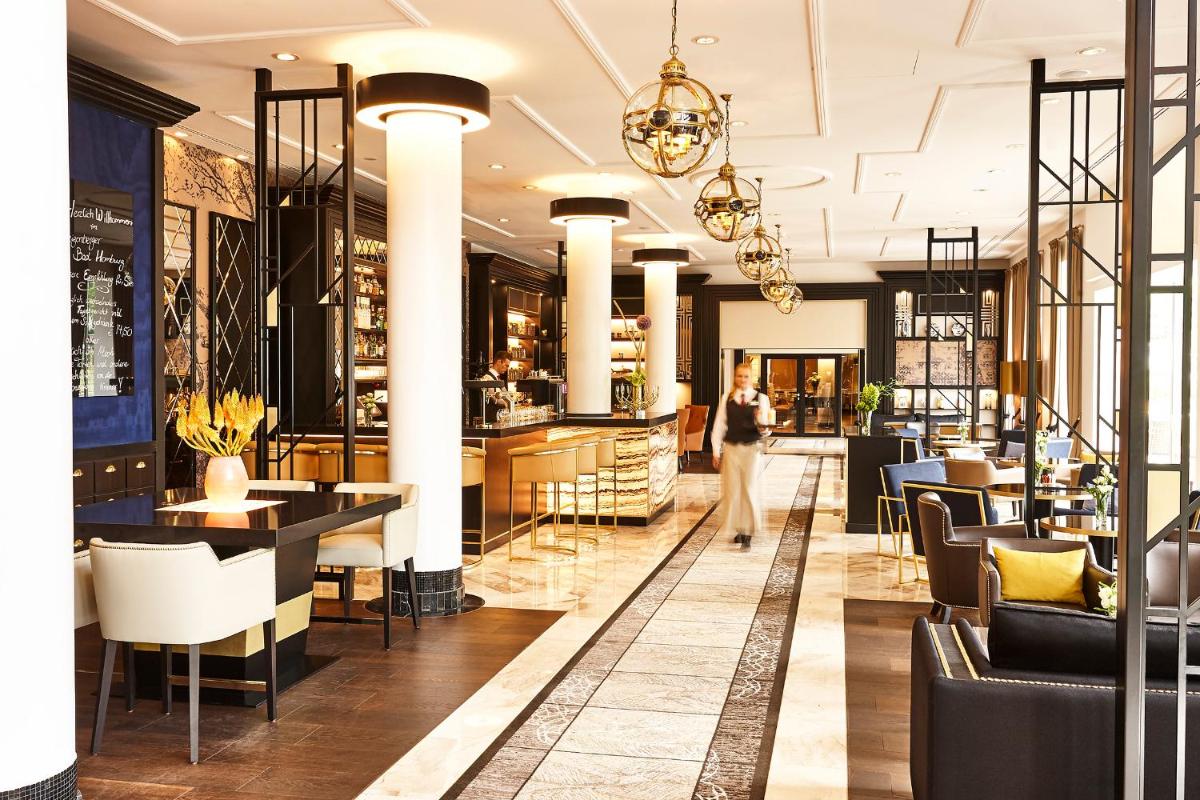 eine Lobby eines Restaurants mit Tischen und Stühlen in der Unterkunft Steigenberger Hotel Bad Homburg in Bad Homburg vor der Höhe eine Lobby eines Restaurants mit Tischen und Stühlen in der Unterkunft Steigenberger Hotel Bad Homburg in Bad Homburg vor der Höhe