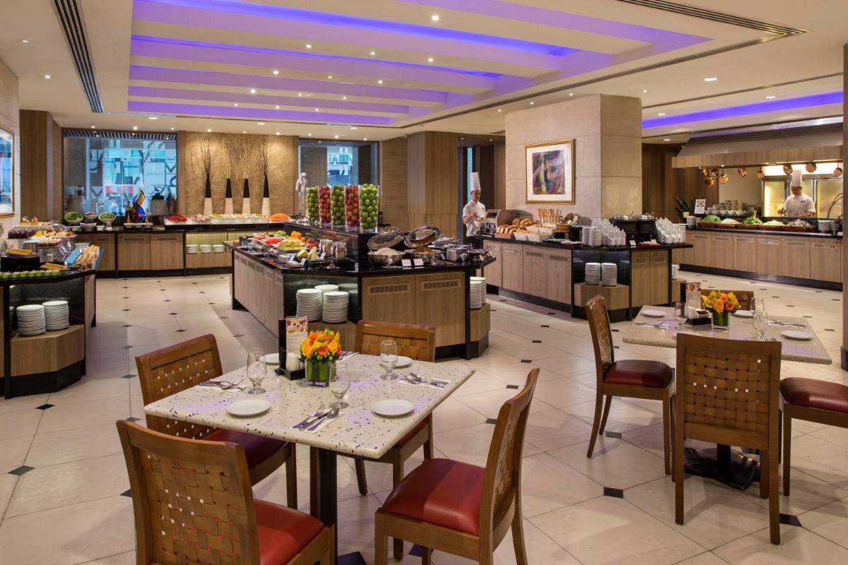 a restaurant with tables and chairs and a buffet at Carlton Hotel Singapore in Singapore a restaurant with tables and chairs and a buffet at Carlton Hotel Singapore in Singapore