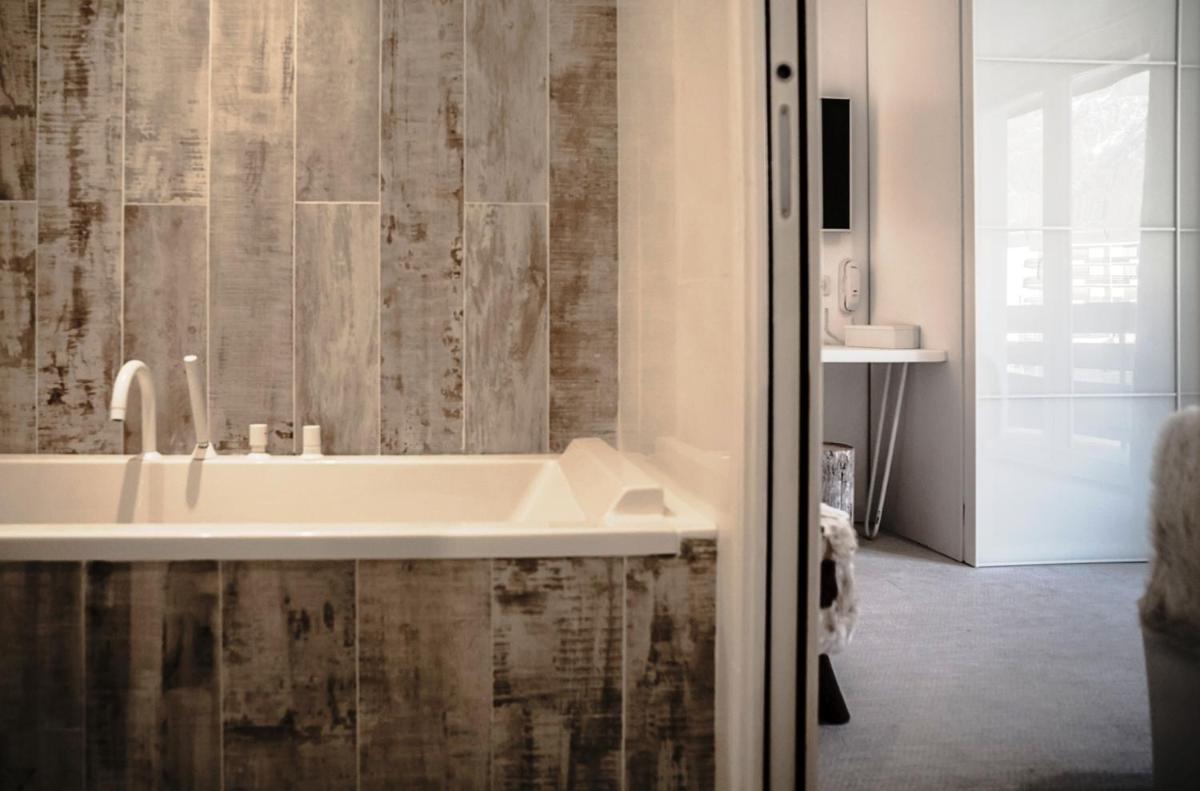 une salle de bain avec une baignoire blanche et une douche dans l'établissement Rock Noir & Spa, à La Salle Les Alpes