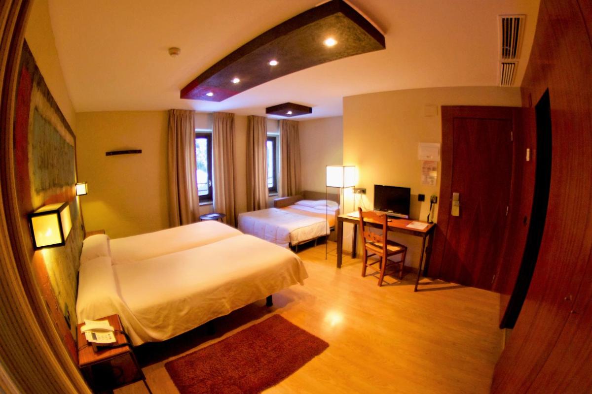 Un dormitorio con una cama y un escritorio con una computadora. en Hotel Santa Cristina Petit Spa, en Canfranc-Estación
