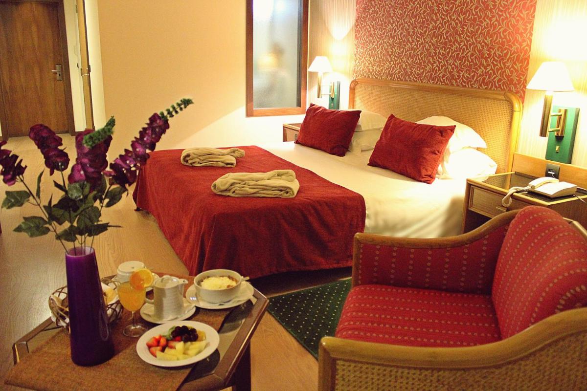 um quarto de hotel com uma cama, uma cadeira e uma mesa em Palace Hotel & Spa - Termas de Sao Vicente em Penafiel mais 30 fotografias