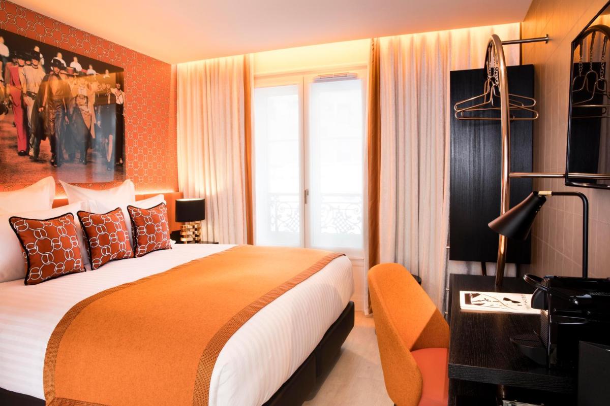 une chambre avec un grand lit et un mur orange dans l'établissement Hôtel Dress Code, à Paris 87 autres photos