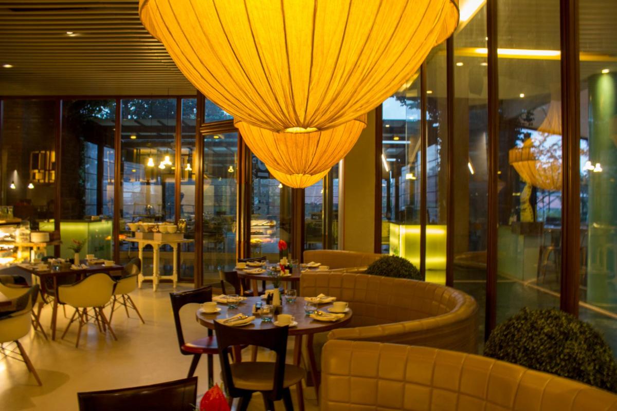 a restaurant with tables and chairs and chandeliers at Hotel Royal Orchid Bangalore in Bengaluru a restaurant with tables and chairs and chandeliers at Hotel Royal Orchid Bangalore in Bengaluru