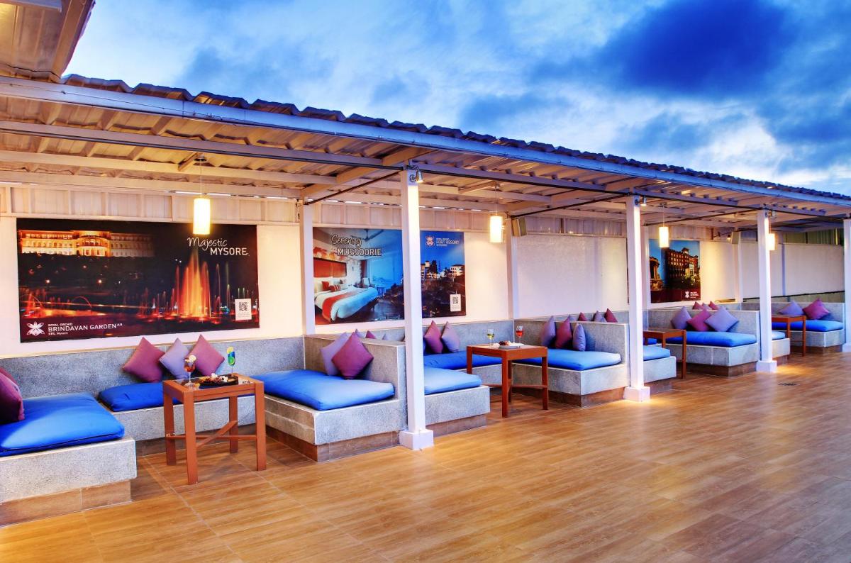 a bar with blue couches and tables on a wooden floor at Hotel Royal Orchid Bangalore in Bengaluru