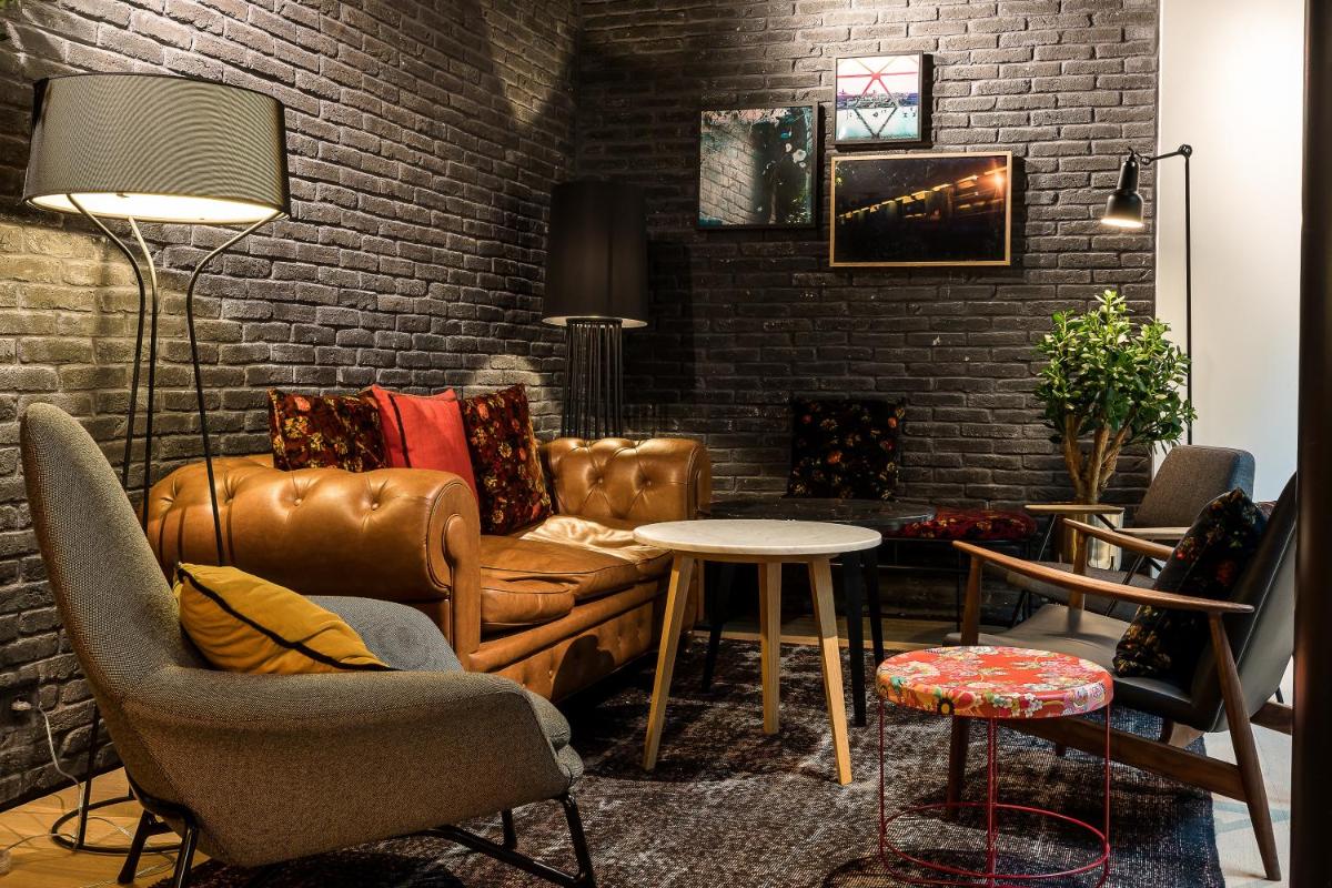 un salon avec un canapé et un mur de briques dans l'établissement Laz' Hotel Spa Urbain Paris, à Paris