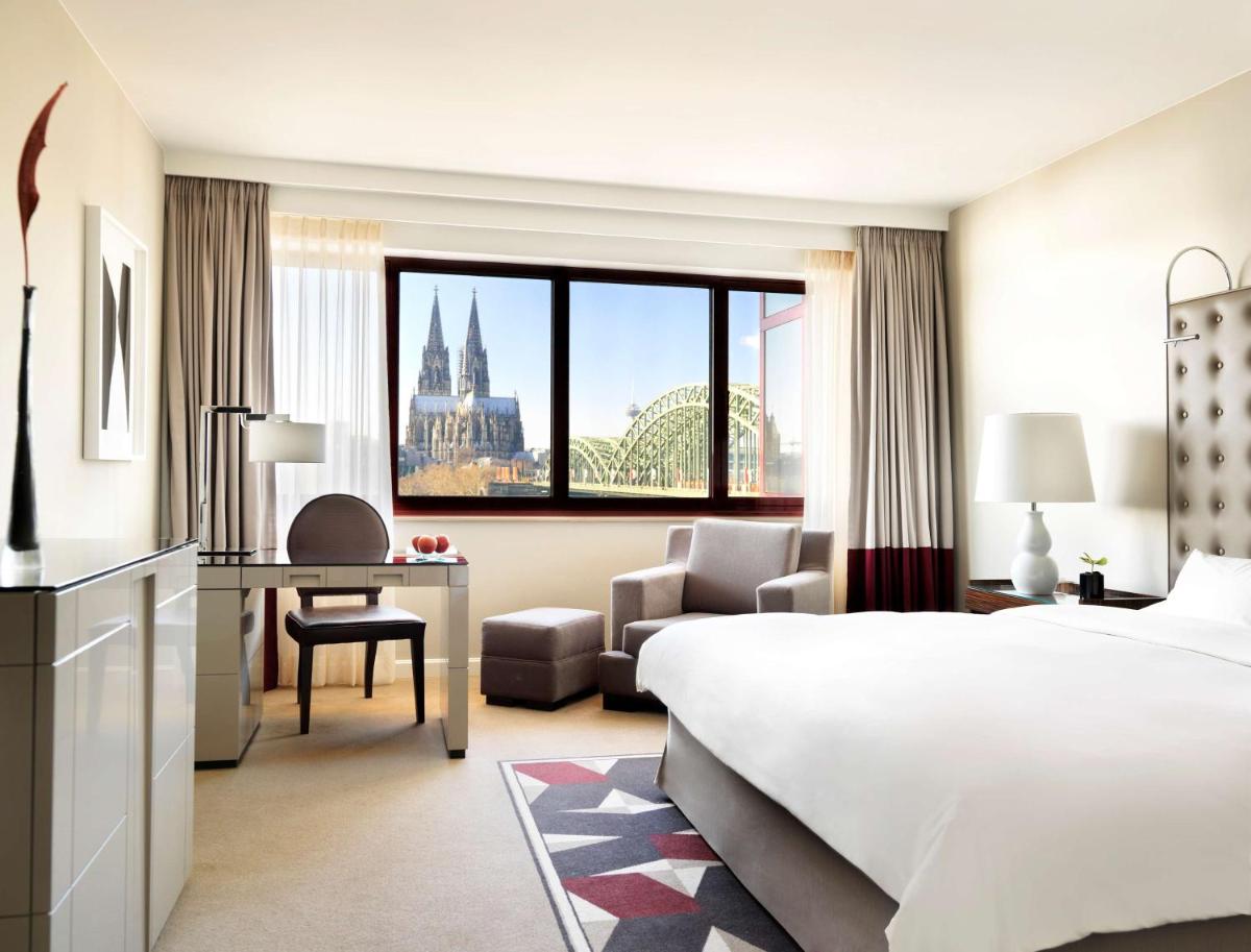 ein Hotelzimmer mit einem Bett, einem Schreibtisch und einem Schlafzimmer in der Unterkunft Hyatt Regency Köln in Köln ein Hotelzimmer mit einem Bett, einem Schreibtisch und einem Schlafzimmer in der Unterkunft Hyatt Regency Köln in Köln