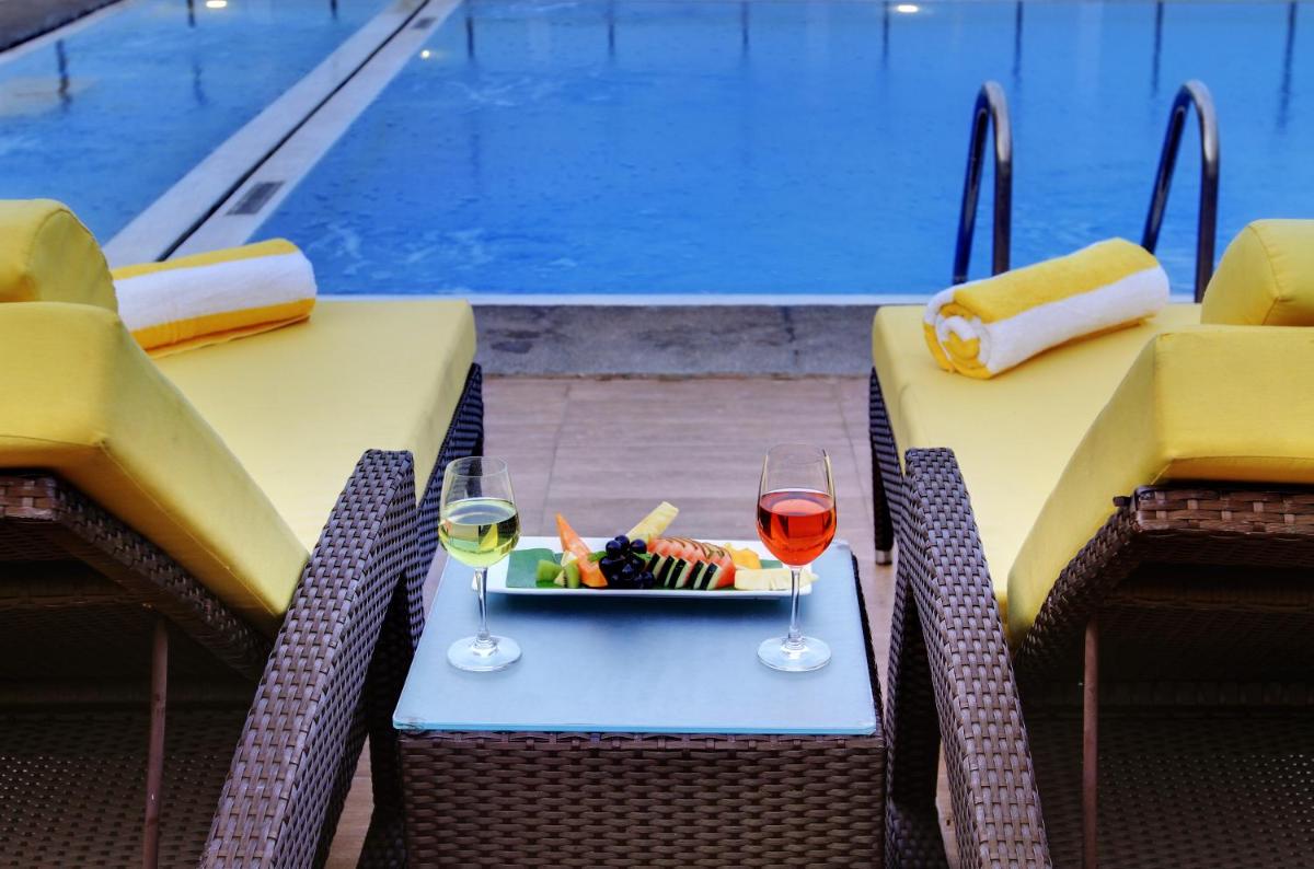 a table with two glasses of wine next to a pool at Hotel Royal Orchid Bangalore in Bengaluru