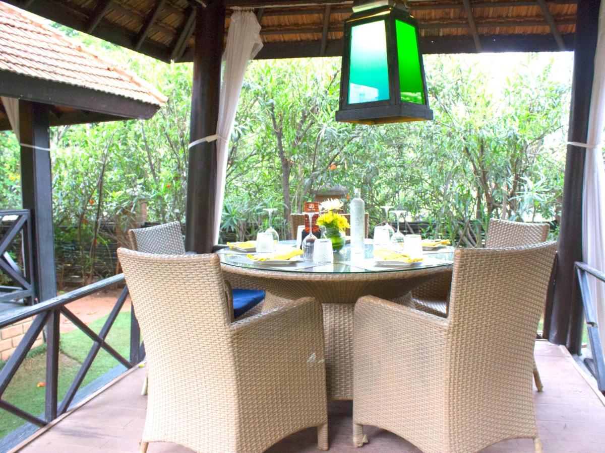 a dining table and chairs on a porch with a view at Hotel Royal Orchid Bangalore in Bengaluru