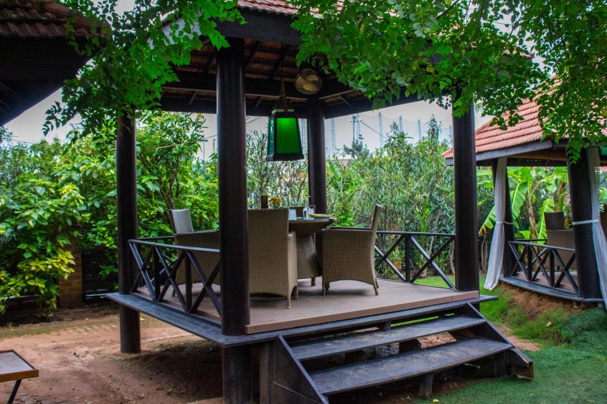 a pavilion with a table and chairs in a garden at Hotel Royal Orchid Bangalore in Bengaluru