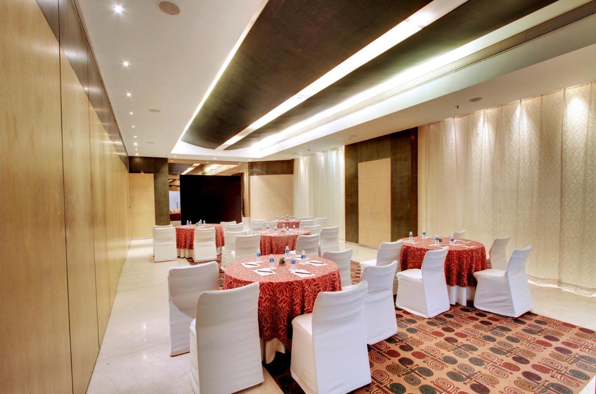a conference room with tables and white chairs and a podium at Hotel Royal Orchid Bangalore in Bengaluru