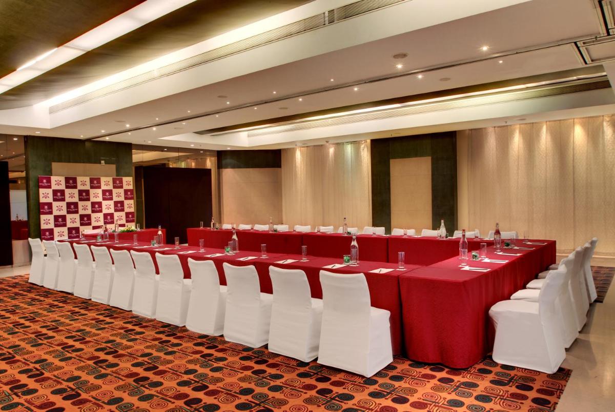 a banquet hall with red and white tables and white chairs at Hotel Royal Orchid Bangalore in Bengaluru