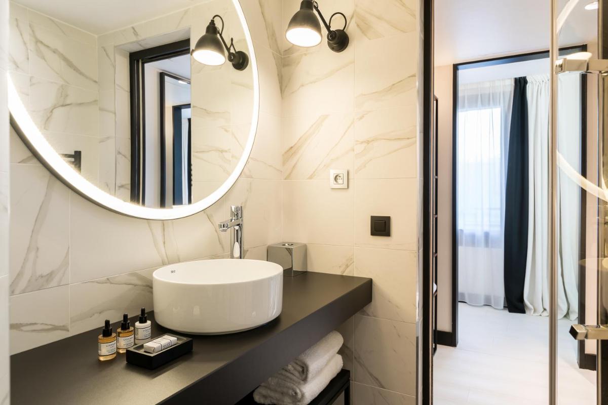 une salle de bain avec un lavabo et un miroir dans l'établissement Laz' Hotel Spa Urbain Paris, à Paris