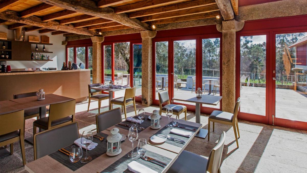 uma sala de jantar com mesas, cadeiras e janelas em Torre de Gomariz Wine & Spa Hotel em Braga
