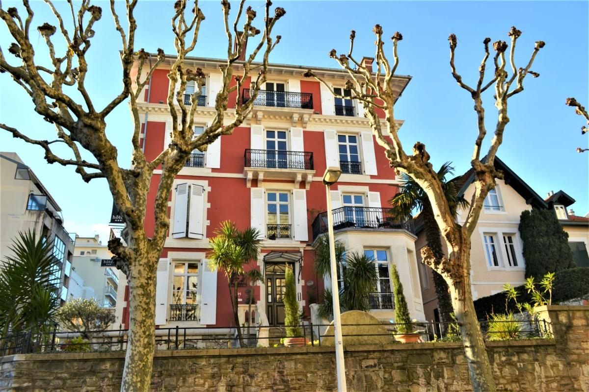 un bâtiment rouge avec des arbres devant dans l'établissement Hôtel & Espace Bien-être La Maison du Lierre, à Biarritz